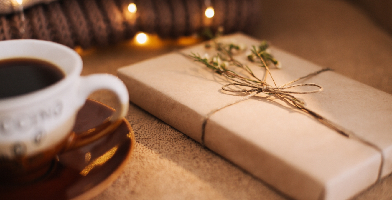 cup of coffee next to a book wrapped as a gift.