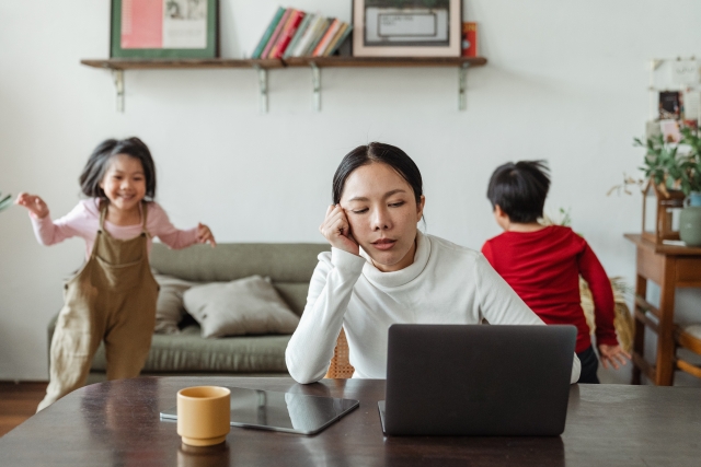 Photo of mother working from home with kids playing