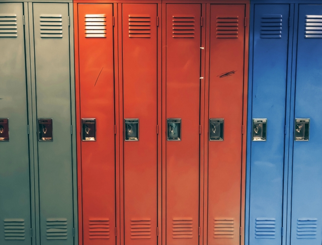 A row of tall school lockers in grey, red, and blue colors