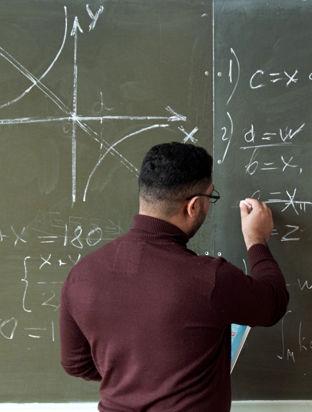 professor writing mathematical notation on chalkboard