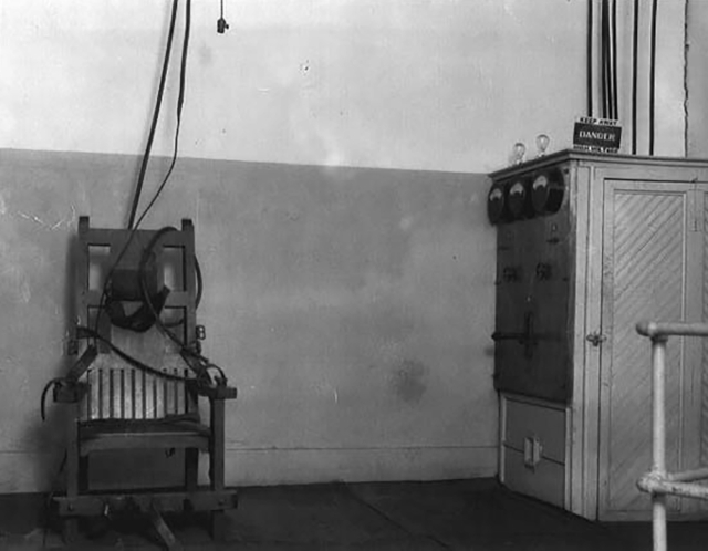 black and white photo of electric chair in an empty room