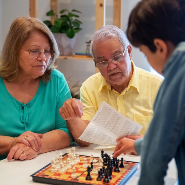 Boy and his grandparents going over Chess rules