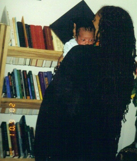 Author in graduation cap and gown holding baby