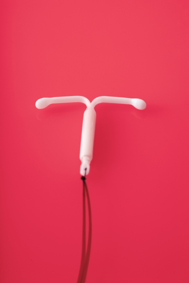 An IUD on a pink-red background