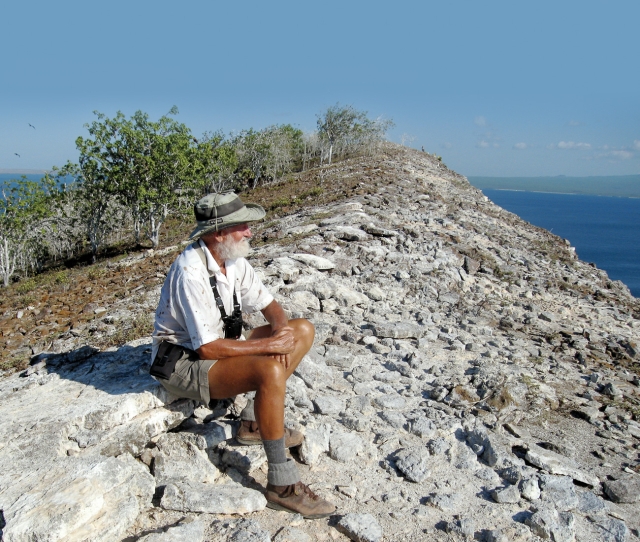 Author Peter Grant sitting on a rocky slope looking out towards the sea