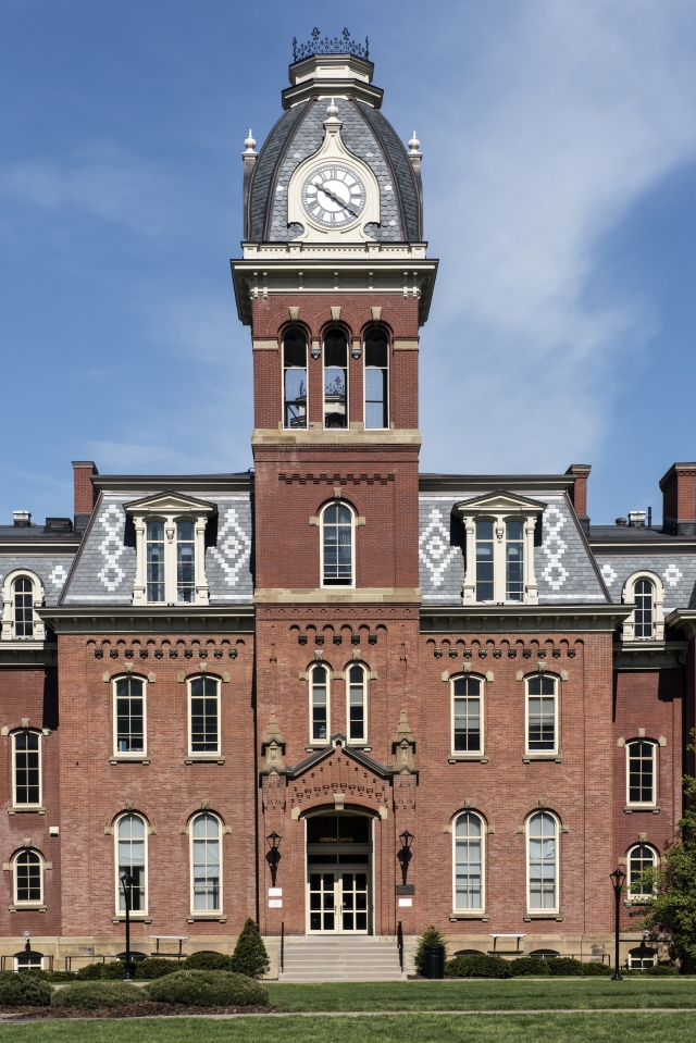 Photograph of Woodburn Hall on the campus of West Virginia University. The building has a red brick facade with a tall central clock tower.