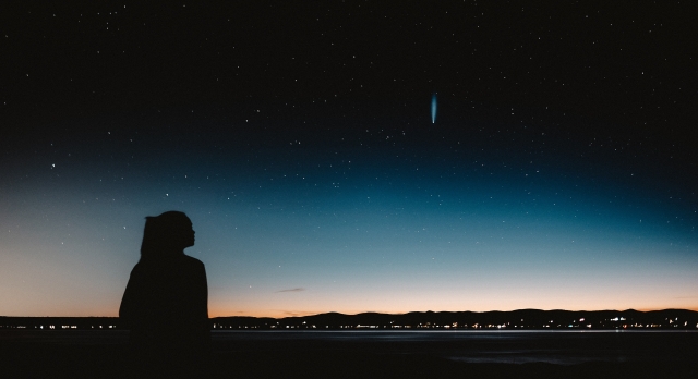A photograph of a woman silhouetted against a night sky with stars