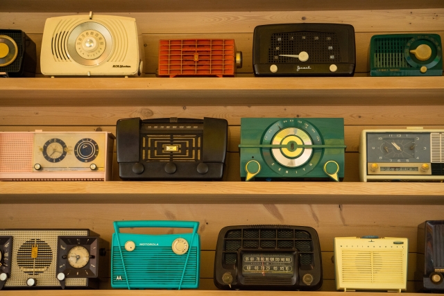 A collection of vintage radios on wooden shelves