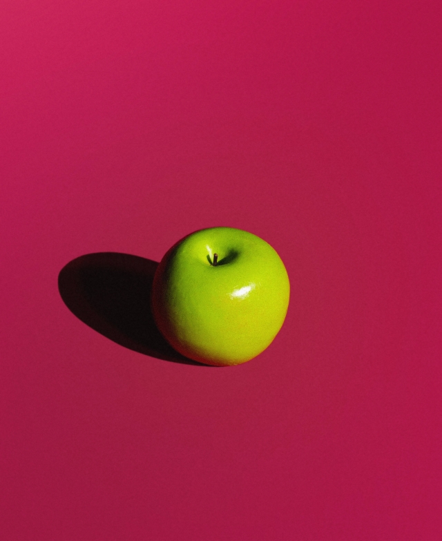 Green apple on magenta background