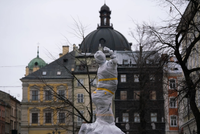 A photograph of a statue wrapped in plastic and tape