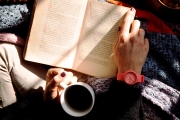 Close up photo of a person reading and drinking coffee
