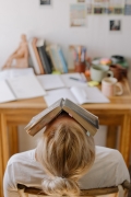 Photo of person sitting with book covering their face