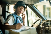A delivery woman takes notes while sitting in a delivery van